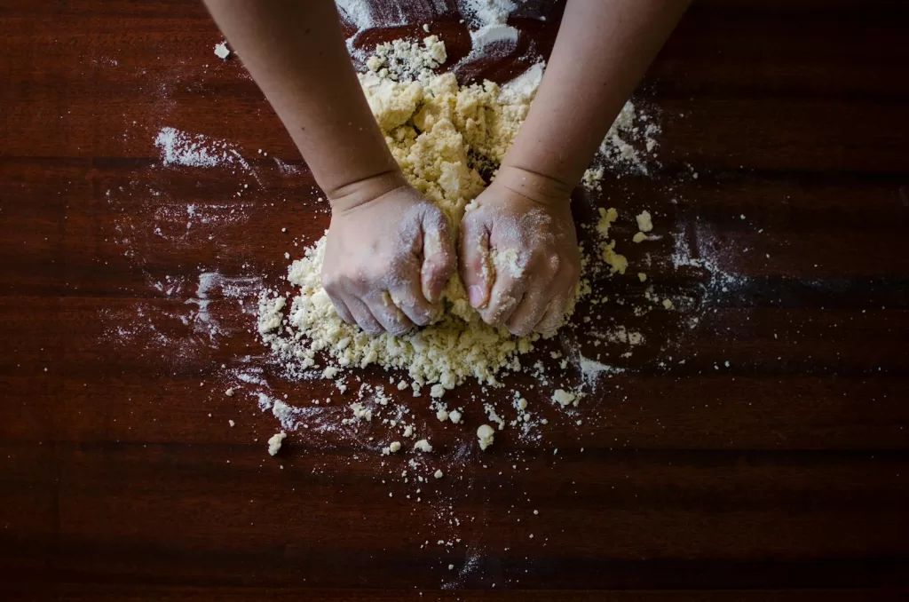 Close-up of hands kneading dough for baking on a wooden table, ideal for cooking themes.